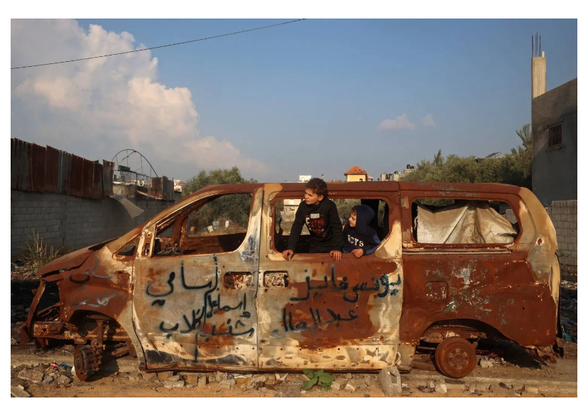 صبي فلسطيني يلعب داخل سيارة دمرتها غارة جوية إسرائيلية في مدينة غزة (أ.ف.ب)