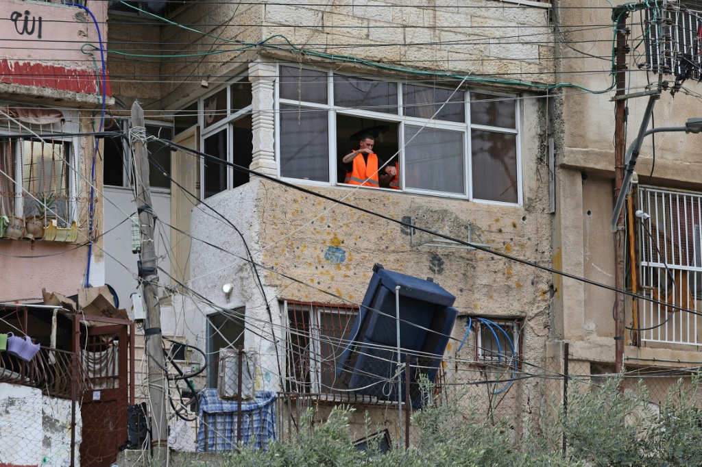 موظف إسرائيلي يلقي أريكة من نافذة منزل فلسطيني، بينما يتم إخلاء إحدى عشرة عائلة من منطقة بطن الهوى ليحل محلهم مستوطنون إسرائيليون في حي سلوان ذي الأغلبية العربية في القدس الشرقية المحتلة، في 25 آذار/مارس 2026 (ا ف ب)
