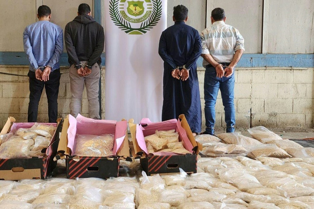 صورة وزعتها وكالة أنباء السعودية في 25 نيسان/أبريل 2023 تظهر مشتبها بهم مكبلين وأكياسا من حبوب الأمفيتامين ضبطتها الشرطة خلال عملية في جدة ثاني مدن المملكة (ا ف ب)
