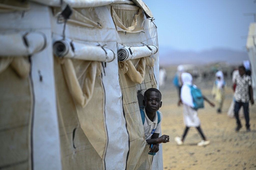 تلميذ سوداني نازح ينظر من داخل خيمة مدرسة ابتدائية يديرها "الائتلاف السوداني للتعليم" بالشراكة مع اليونيسف جنوب بورتسودان في 26 نيسان/أبريل 2026 (ا ف ب)