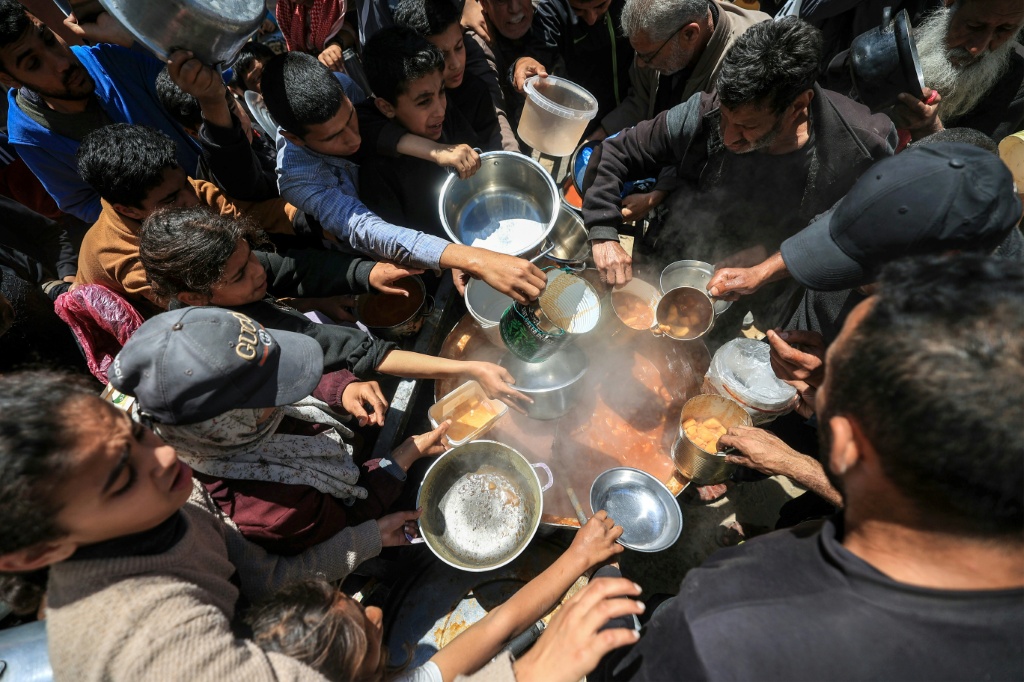 نازحون فلسطينيون يتلقون الطعام من مطبخ خيري في مخيم النصيرات للاجئين وسط قطاع غزة في 22 نيسان/أبريل 2026 (ا ف ب)