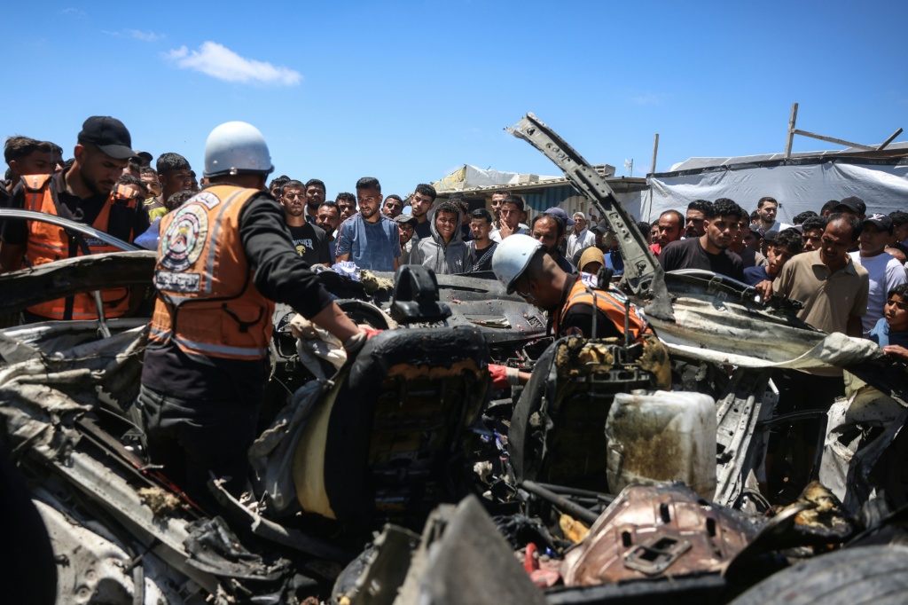عناصر من الدفاع المدني يتفقدون هيكل سيارة أصيبت في غارة إسرائيلية في خان يونس في جنوب قطاع غزة في 26 أيار/مايو 2026 (ا ف ب)