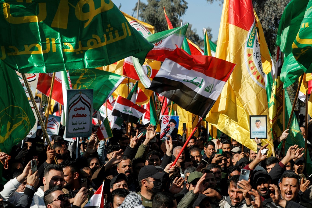 متظاهرون يرفعون أعلام العراق وفصائل مسلحة موالية لإيران في تظاهرة قرب سفارة طهران في بغداد، في 16 كانون الثاني/يناير 2026 (ا ف ب)