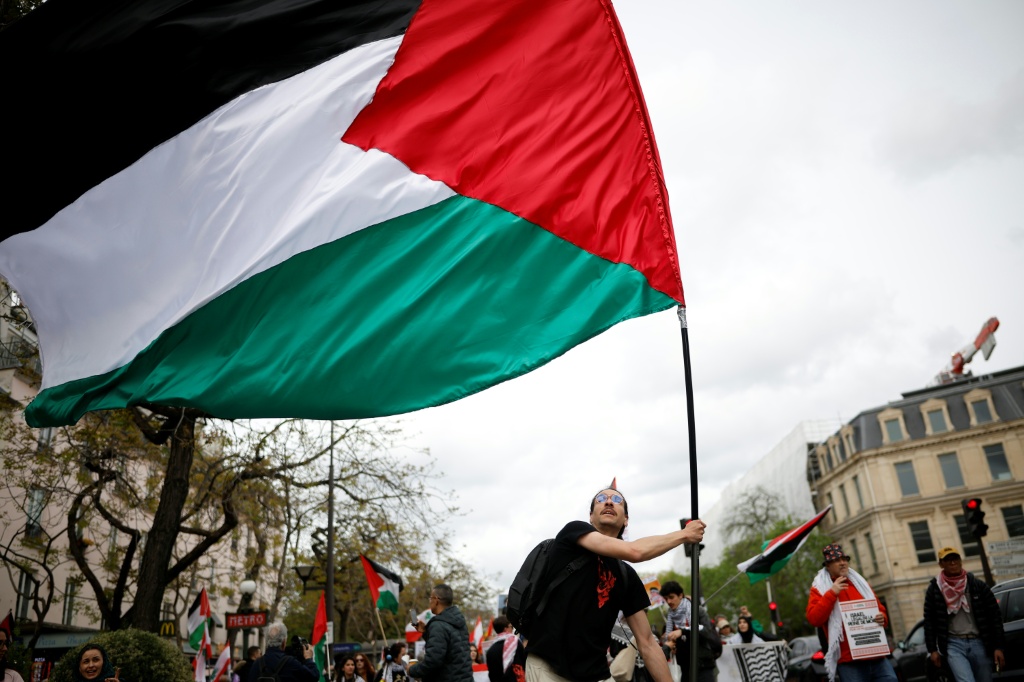 متظاهر يرفع العالم الفلسطيني في باريس بتاريخ 12 نيسان/أبريل 2026 (ا ف ب)