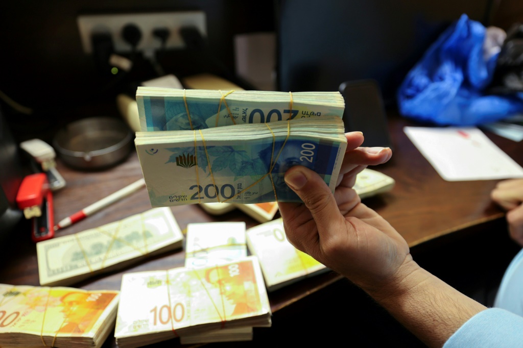 فلسطيني يحمل رزمة من الأوراق النقدية من فئة 200 شيكل في مكتب صيرفة في رام الله في 5 تشرين الأول/أكتوبر 2021 (ا ف ب)